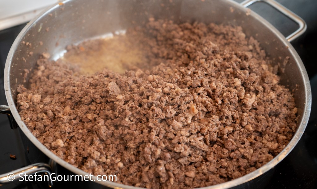 Coarsely ground beef being cooked in a saucepan.