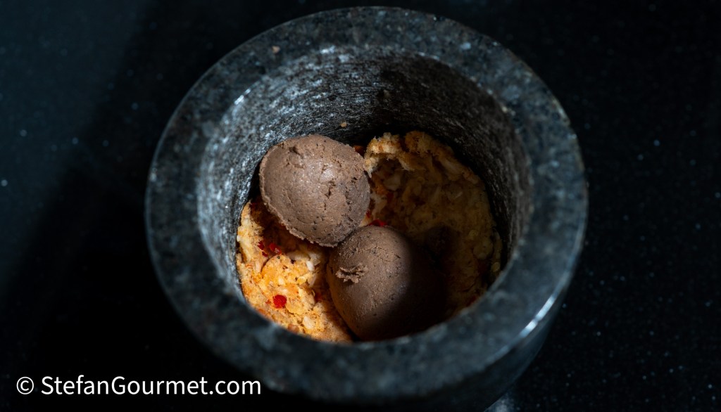 Mortar and pestle containing a mixture for a Thai dip, with small balls of the mixture resting on top.