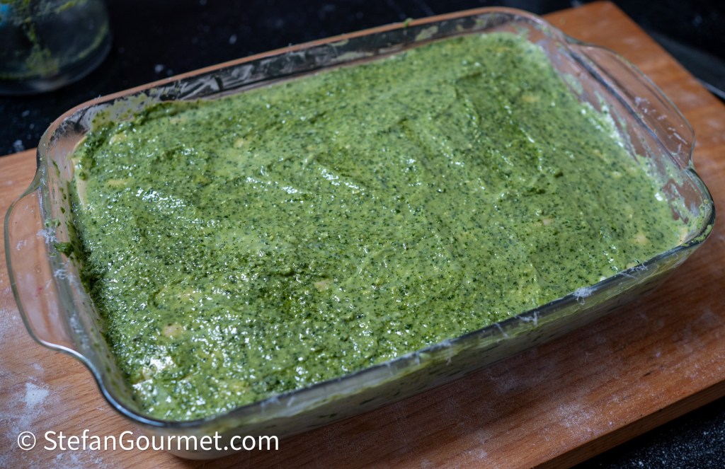 A dish of homemade pesto alla genovese, featuring a vibrant green sauce spread evenly in a glass baking dish.