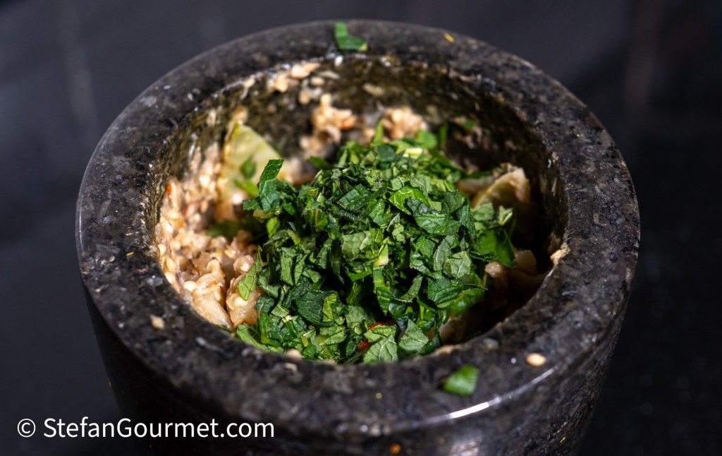 A stone mortar filled with chopped herbs, ready for mixing with other ingredients.