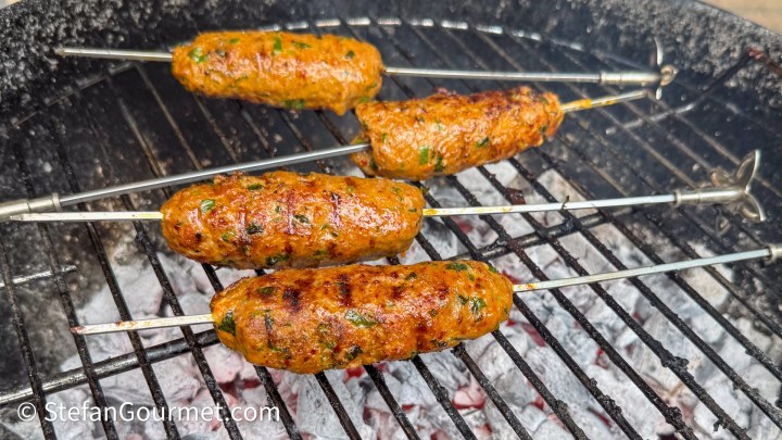 Grilled kebabs on skewers cooking over a charcoal grill.
