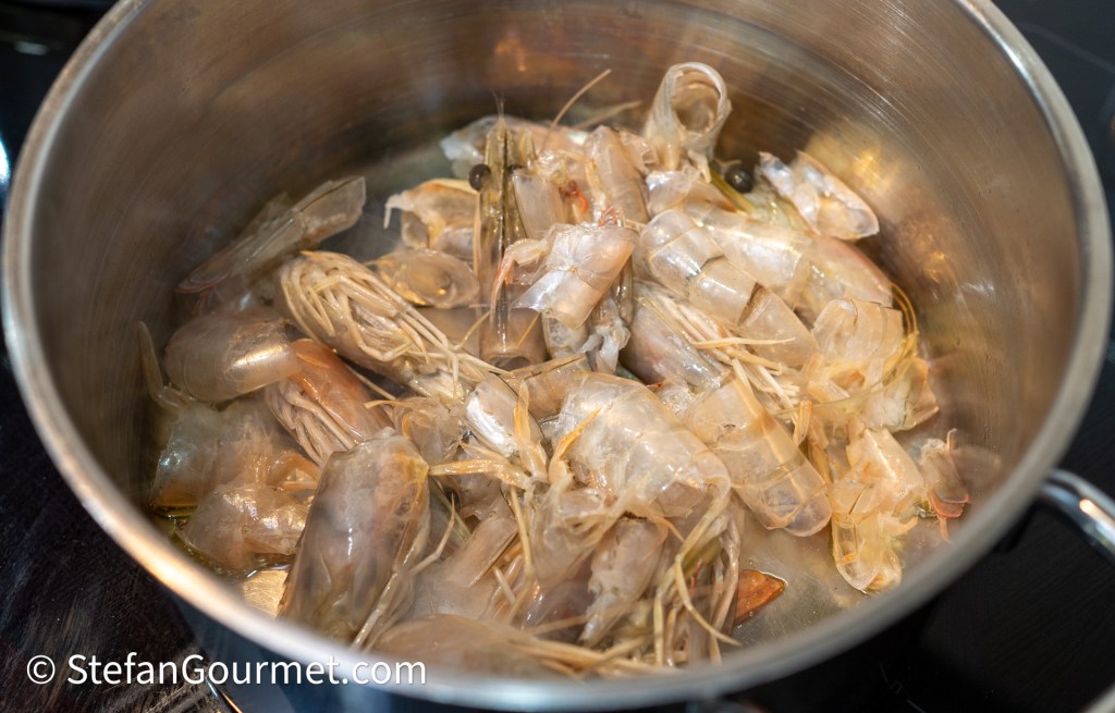 A pot filled with raw shrimp, showing their shells and tails, ready for cooking.