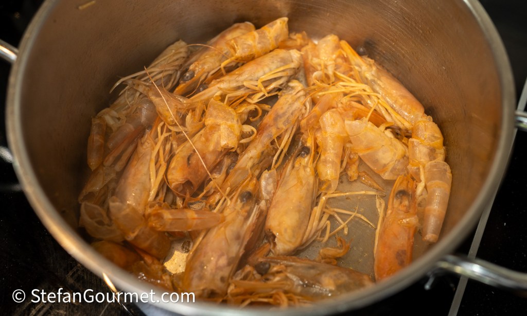 A pot filled with cooked shrimp, showcasing their orange exterior and long antennae.