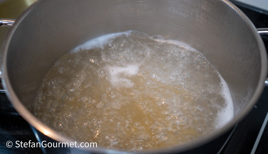 A pot of boiling water with bubbles rising to the surface.