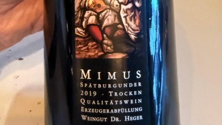 Close-up of a wine bottle labeled 'MIMUS Spätburgunder 2019 Trocken Qualitätswein' with an illustration and details about the winery Dr. Heger.