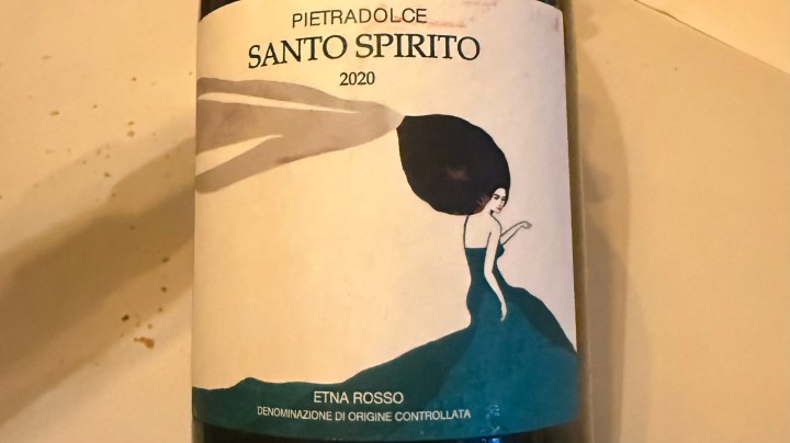 Label of Pietradolce Santo Spirito 2020 Etna Rosso wine, featuring an illustration of a woman in a blue dress with flowing hair.