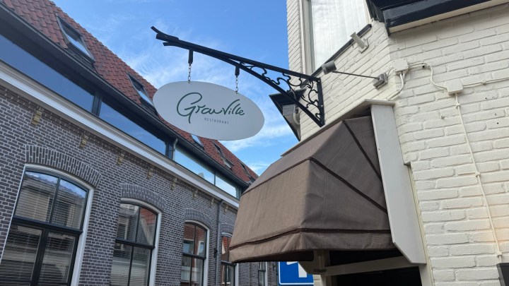 Sign for 'Gronville Restaurant' hanging above the entrance of a building, with a blue sky in the background.