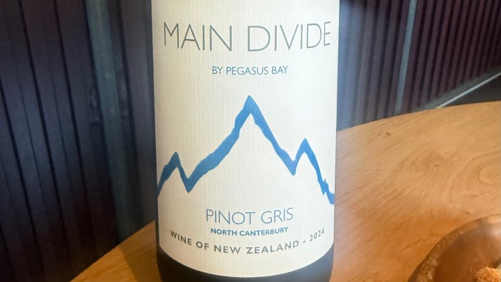 Close-up of a wine bottle labeled 'Main Divide by Pegasus Bay' with a mountain graphic, indicating it is a 'Pinot Gris' from North Canterbury, New Zealand, vintage 2014.