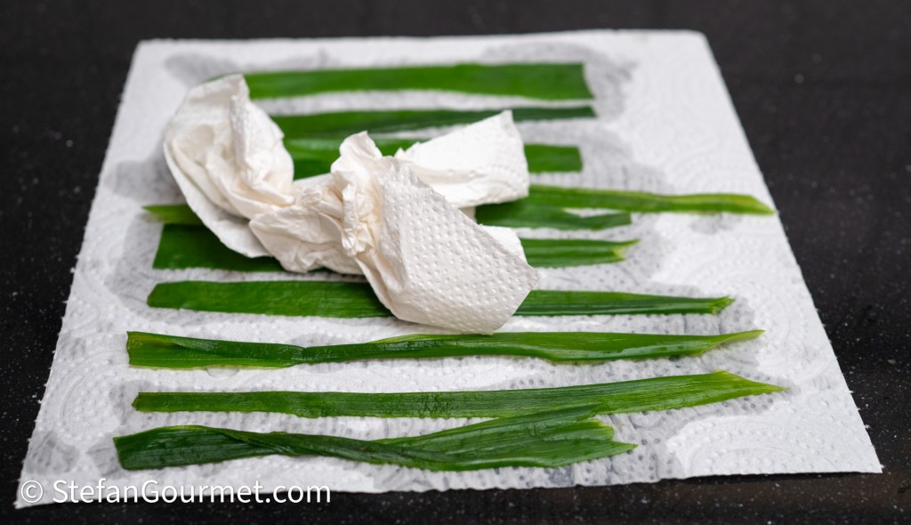 Fresh green herbs arranged on a paper towel with a crumpled paper napkin nearby.